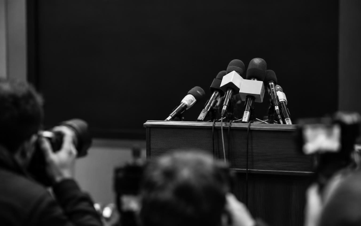Placeholder: microphones at a podium in a technical briefing room